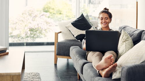 Woman using a laptop on a couch in a bright living room